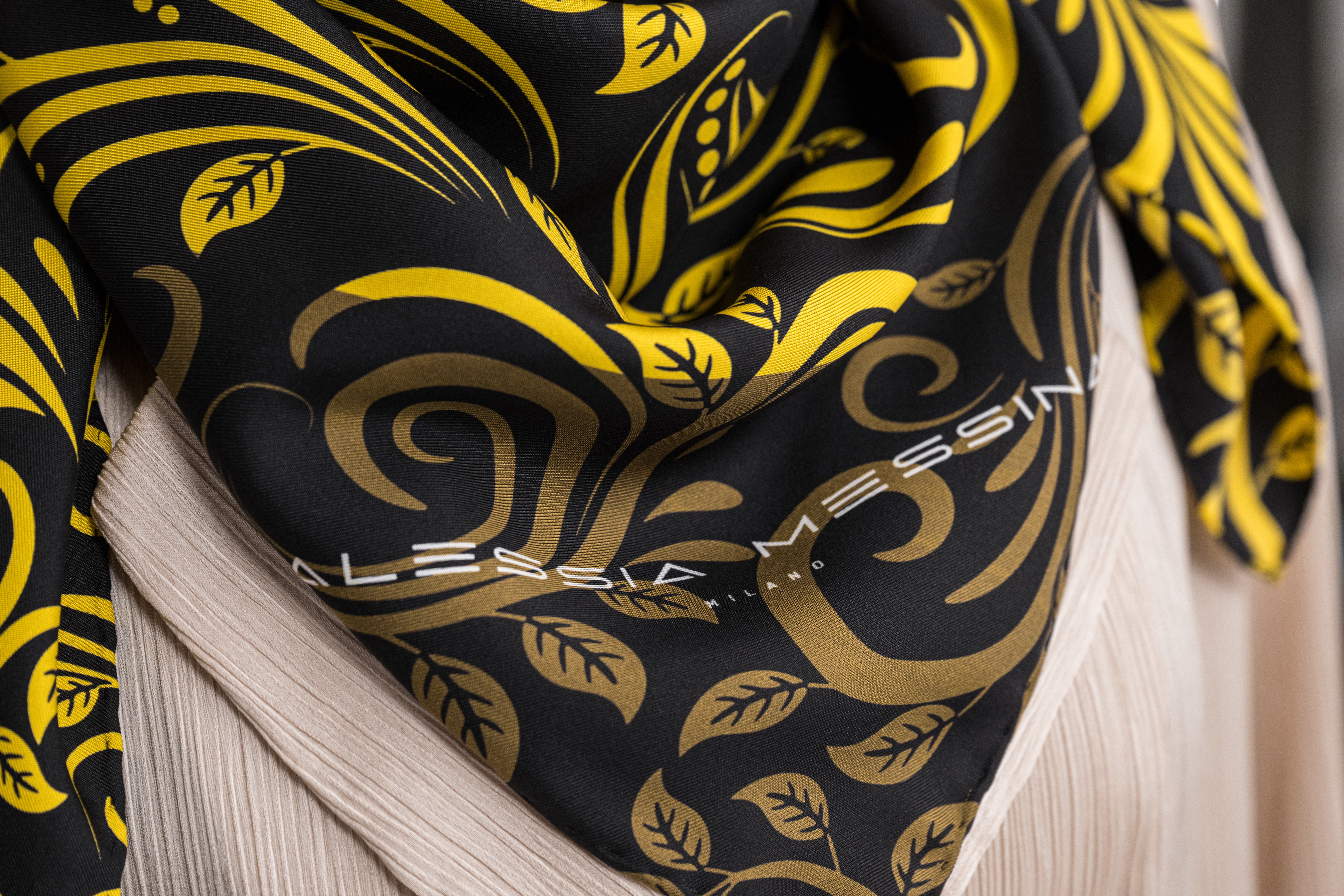 Black fabric with gold ornate patterns and a beige edge.