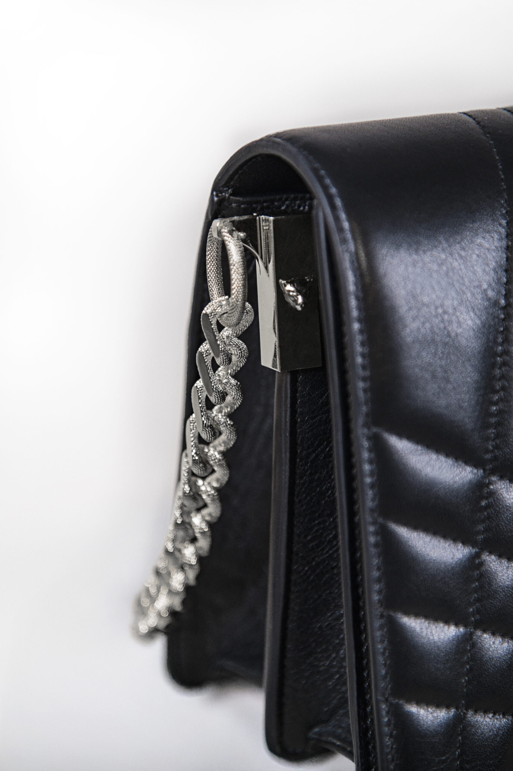 Close-up of a black leather handbag with a silver chain strap.