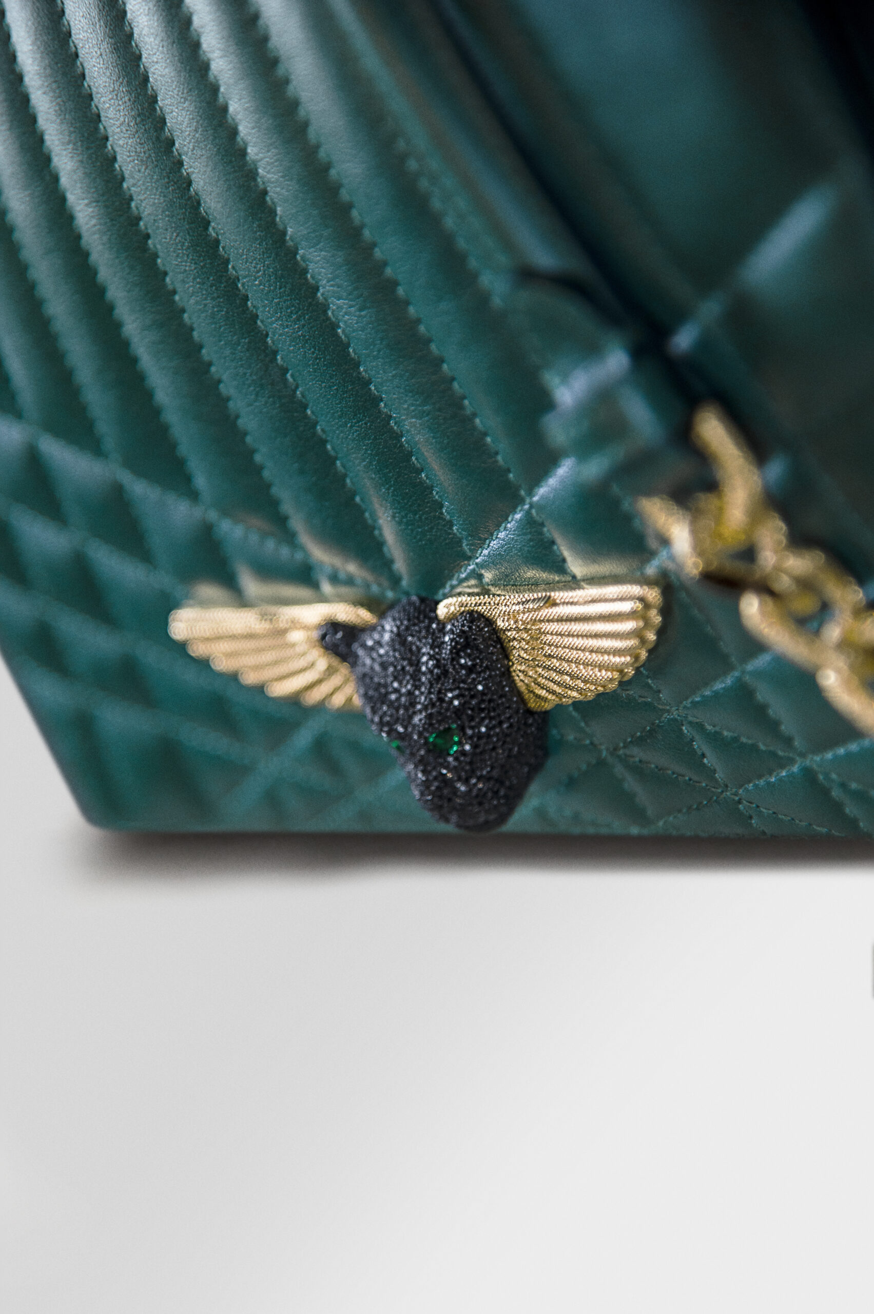 A bee-shaped brooch with gold wings on a green quilted fabric.