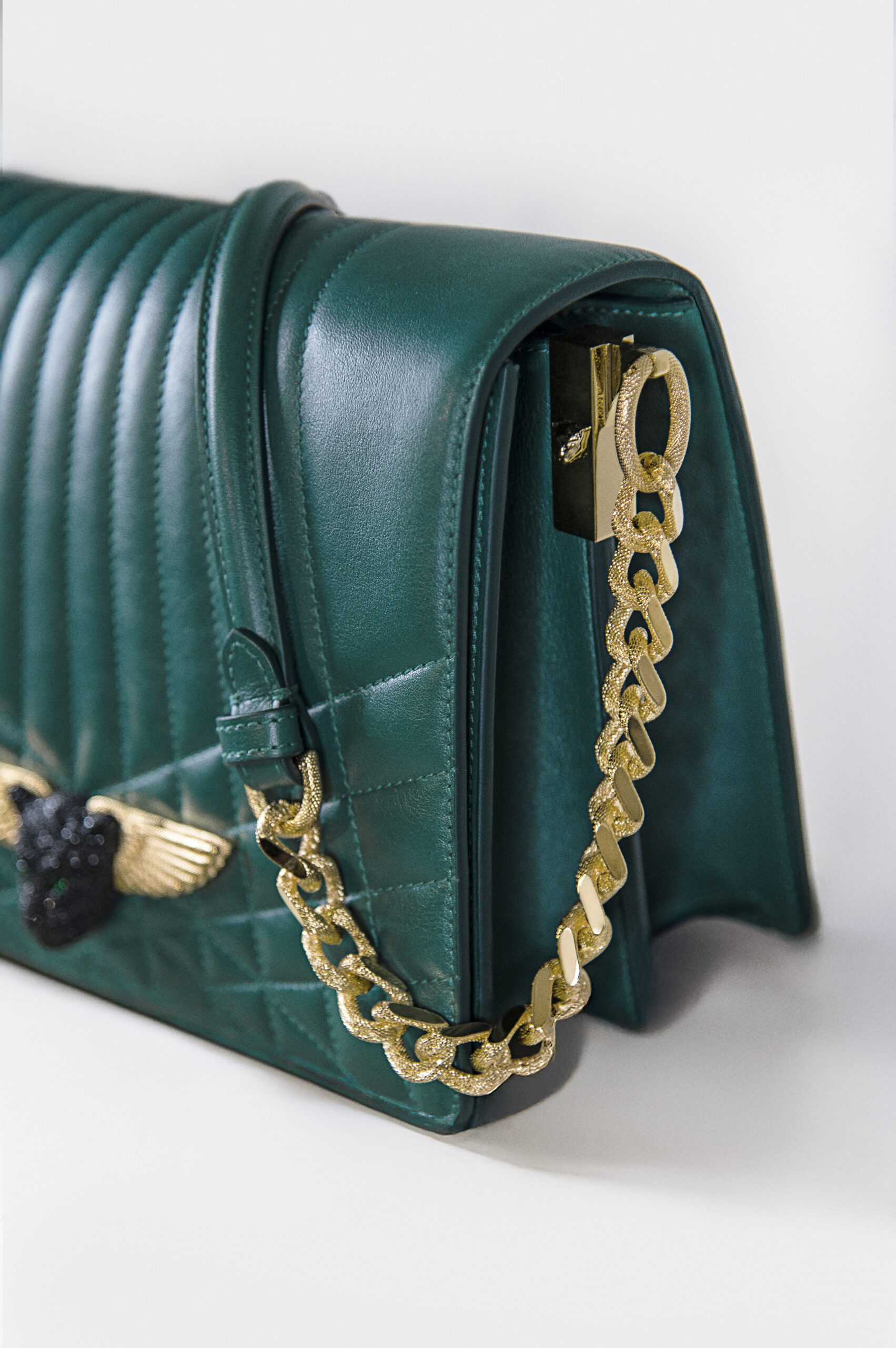 Close-up of a green leather bag with gold chain strap.