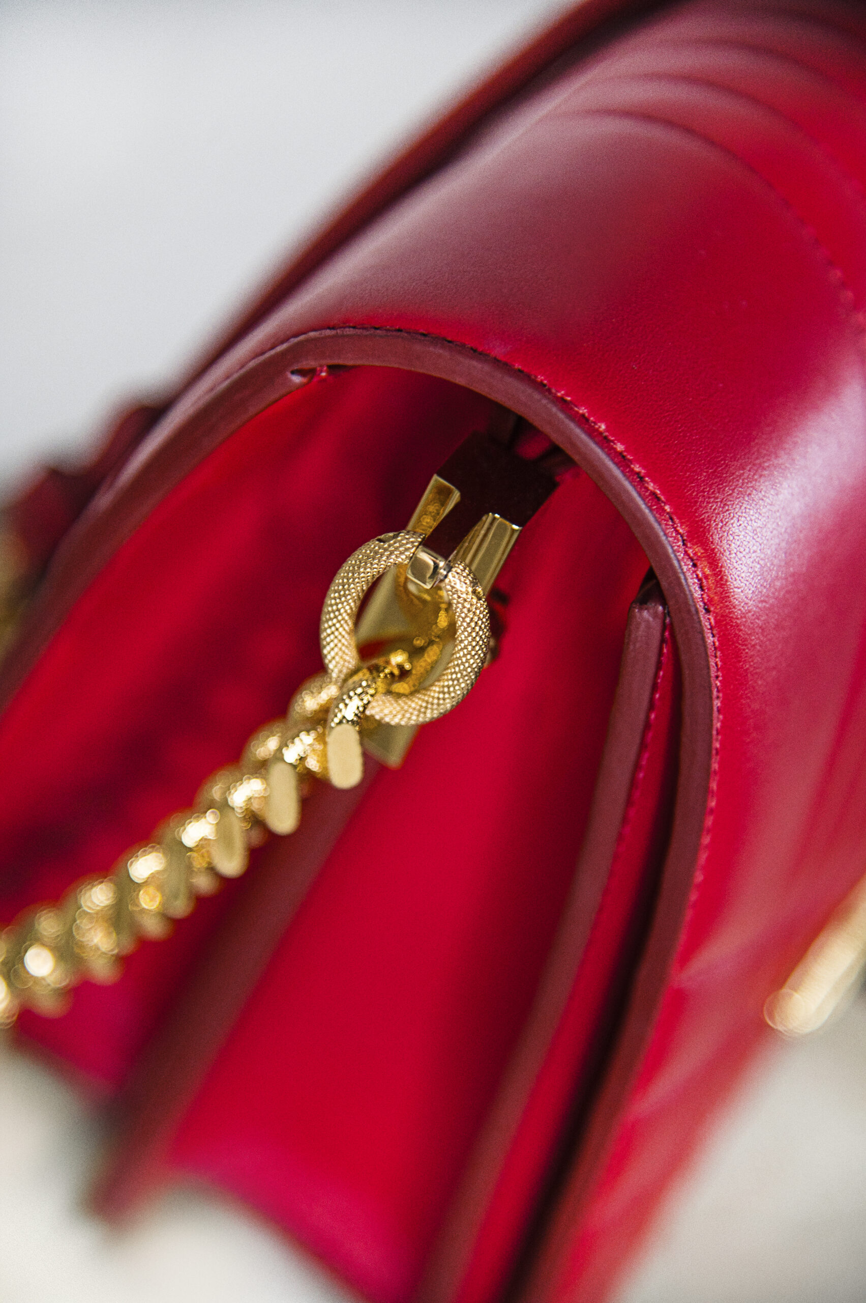 Close-up of a red leather purse with a gold zipper and chain.
