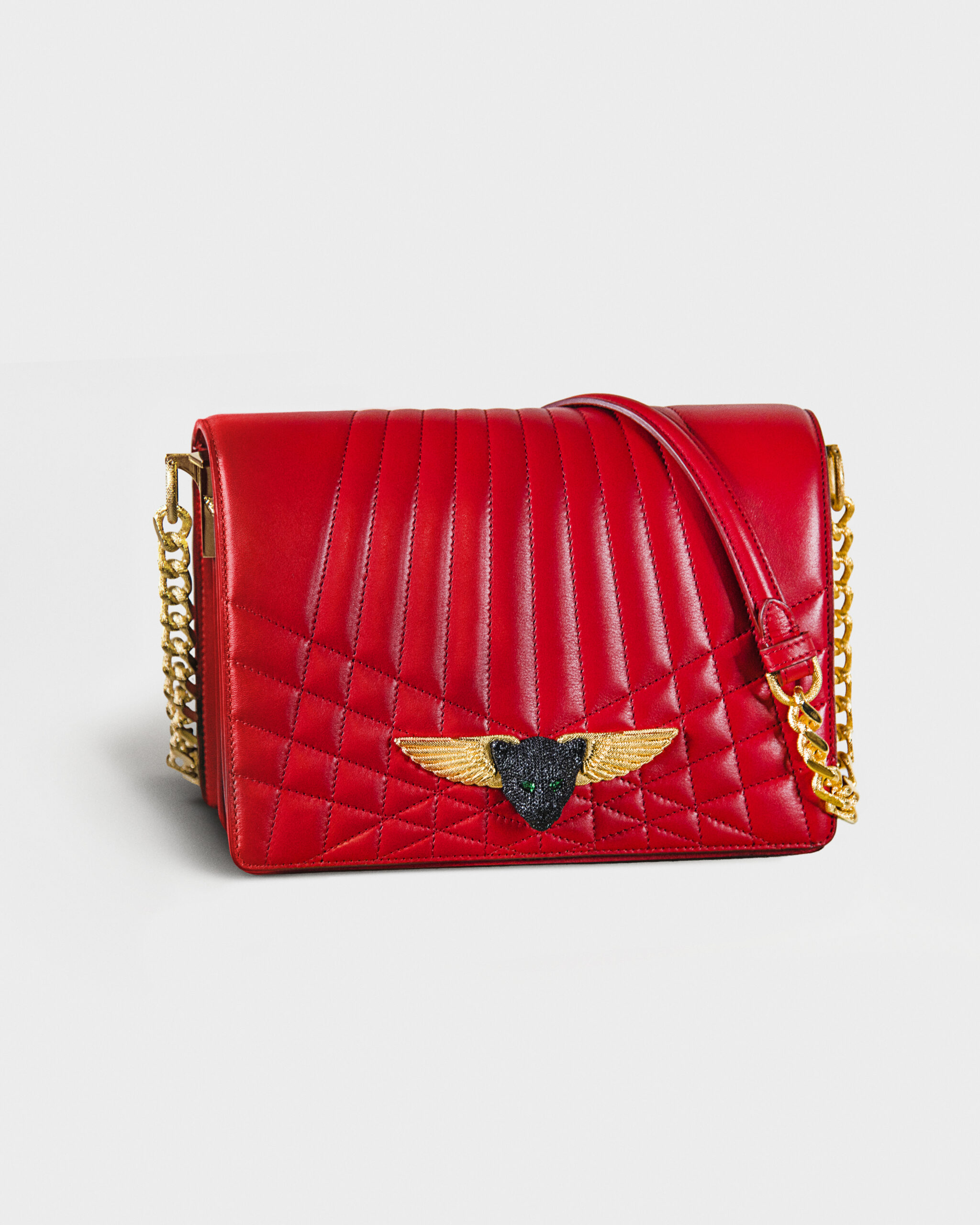 Red quilted leather handbag with gold chain and winged emblem.