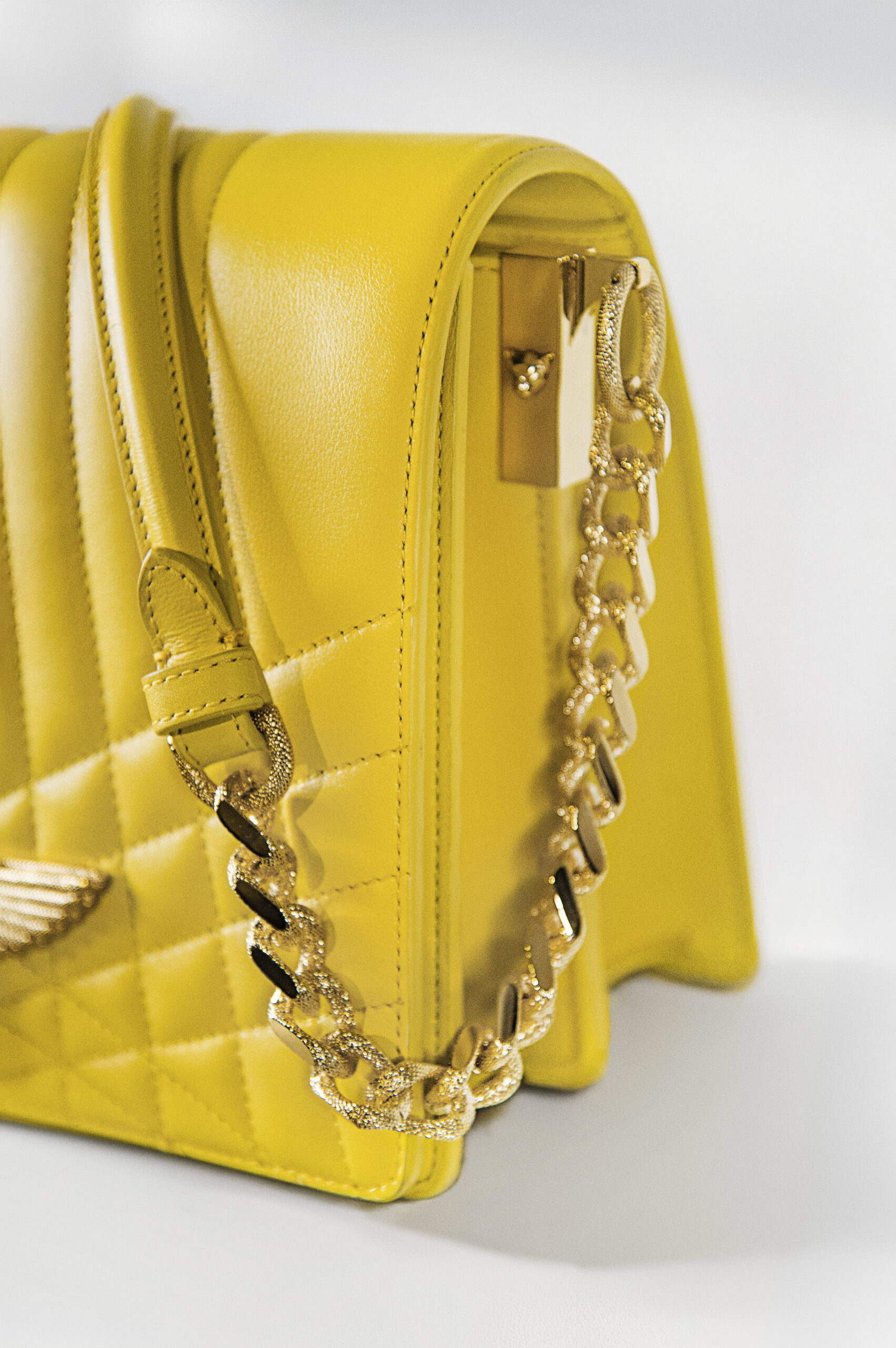 Close-up of a yellow quilted handbag with gold chain and zipper.