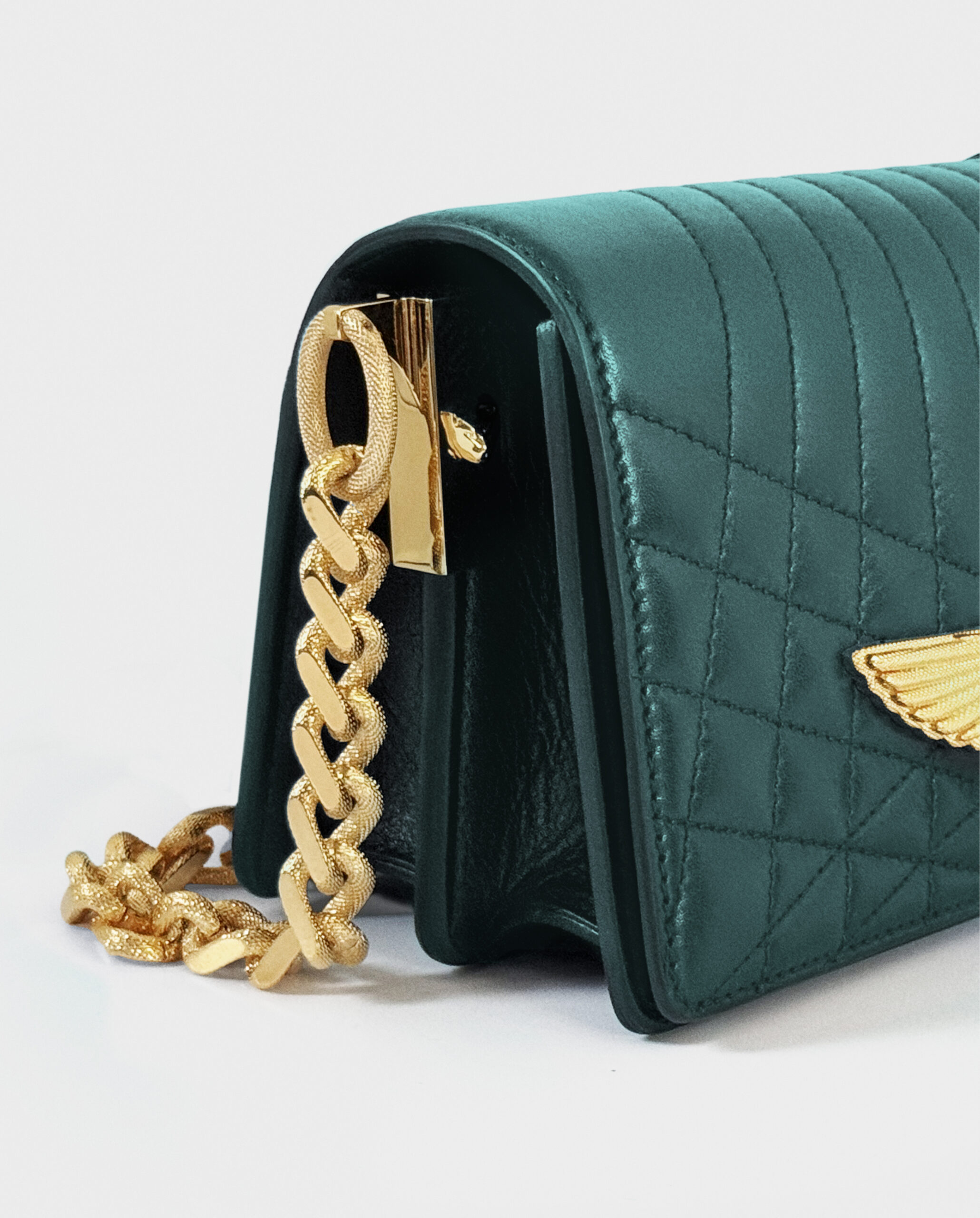 Close-up of a green textured handbag with gold chain and clasp.