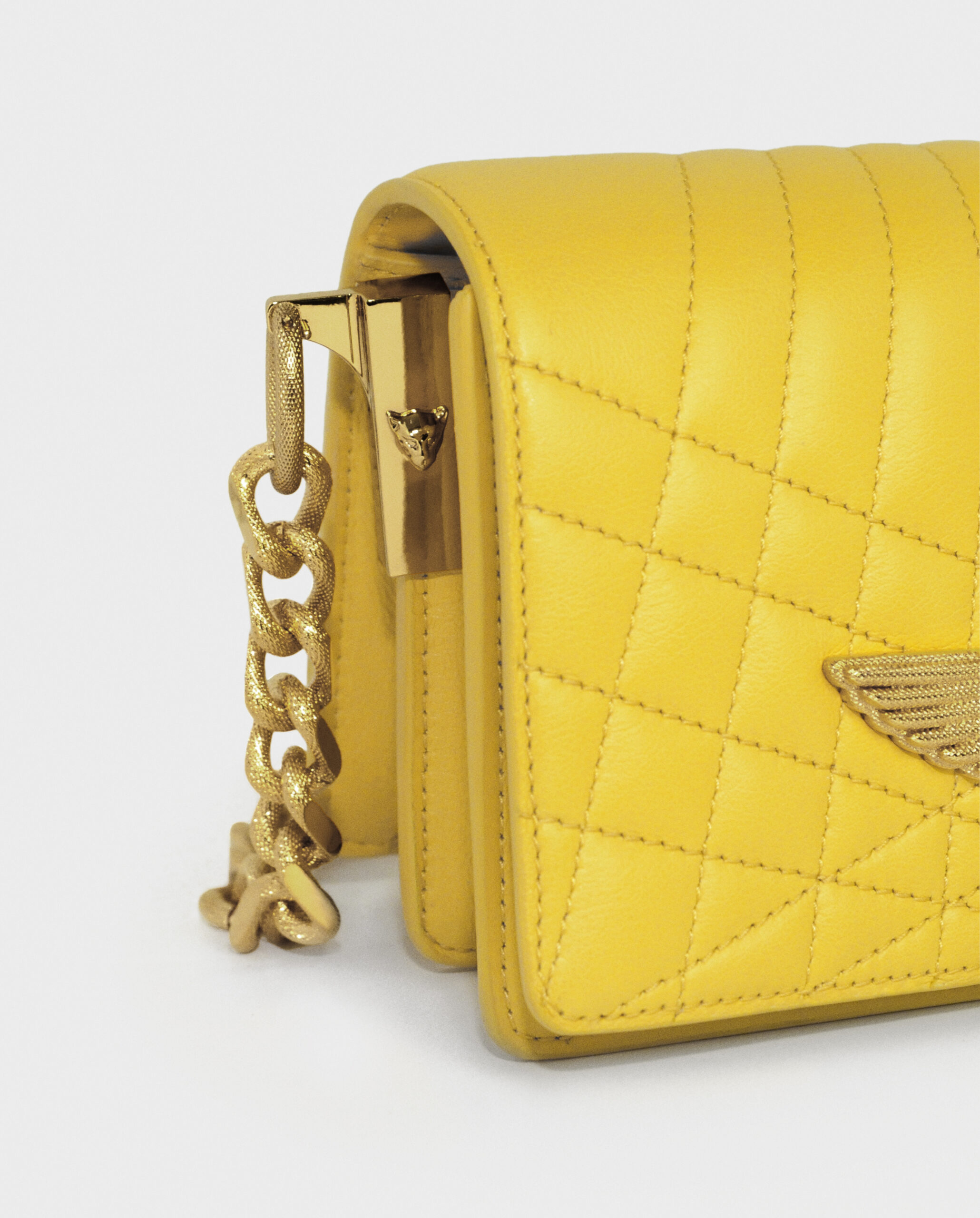 Close-up of a yellow quilted handbag with a gold chain strap.