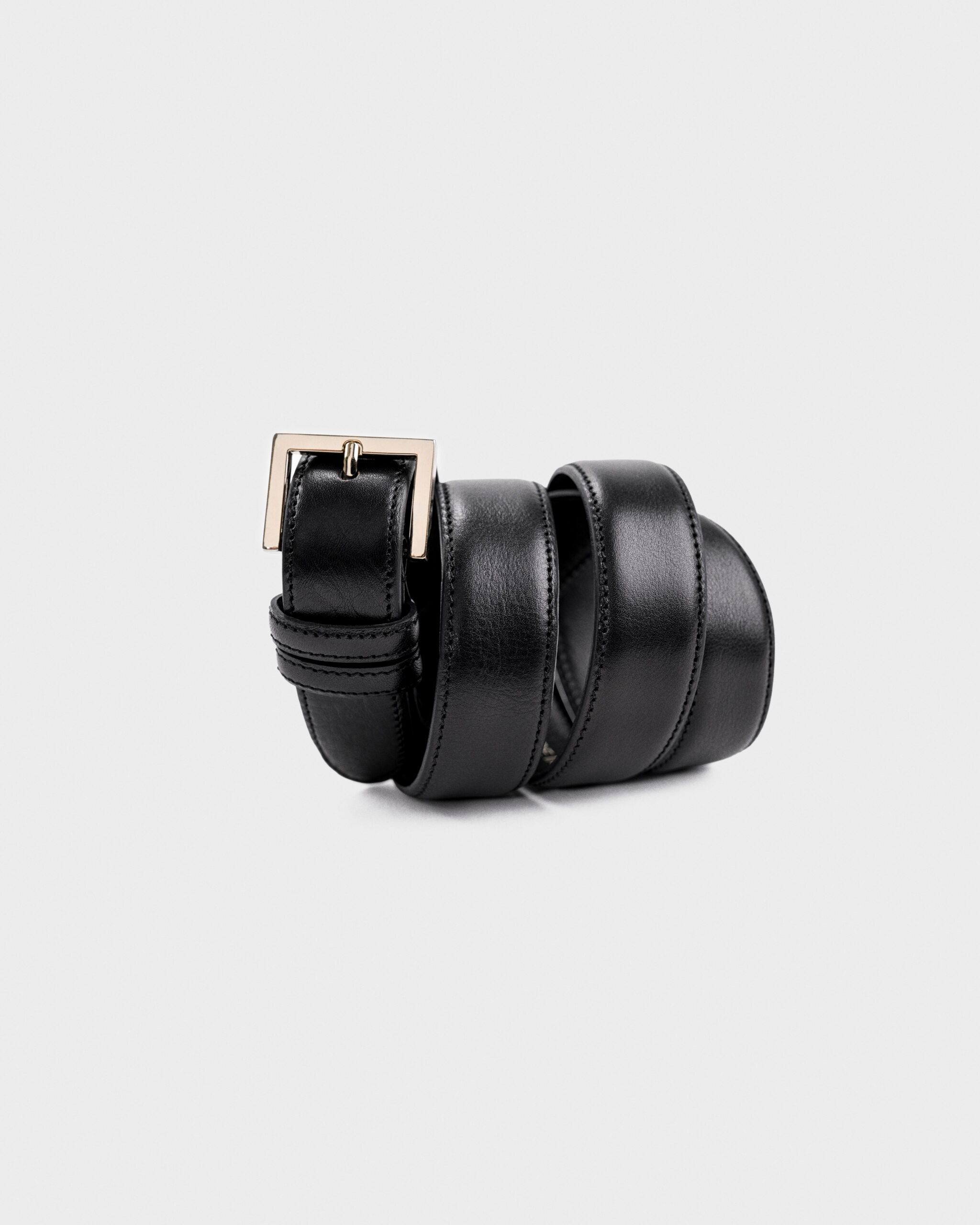 Black leather belt with a gold buckle, rolled up neatly.