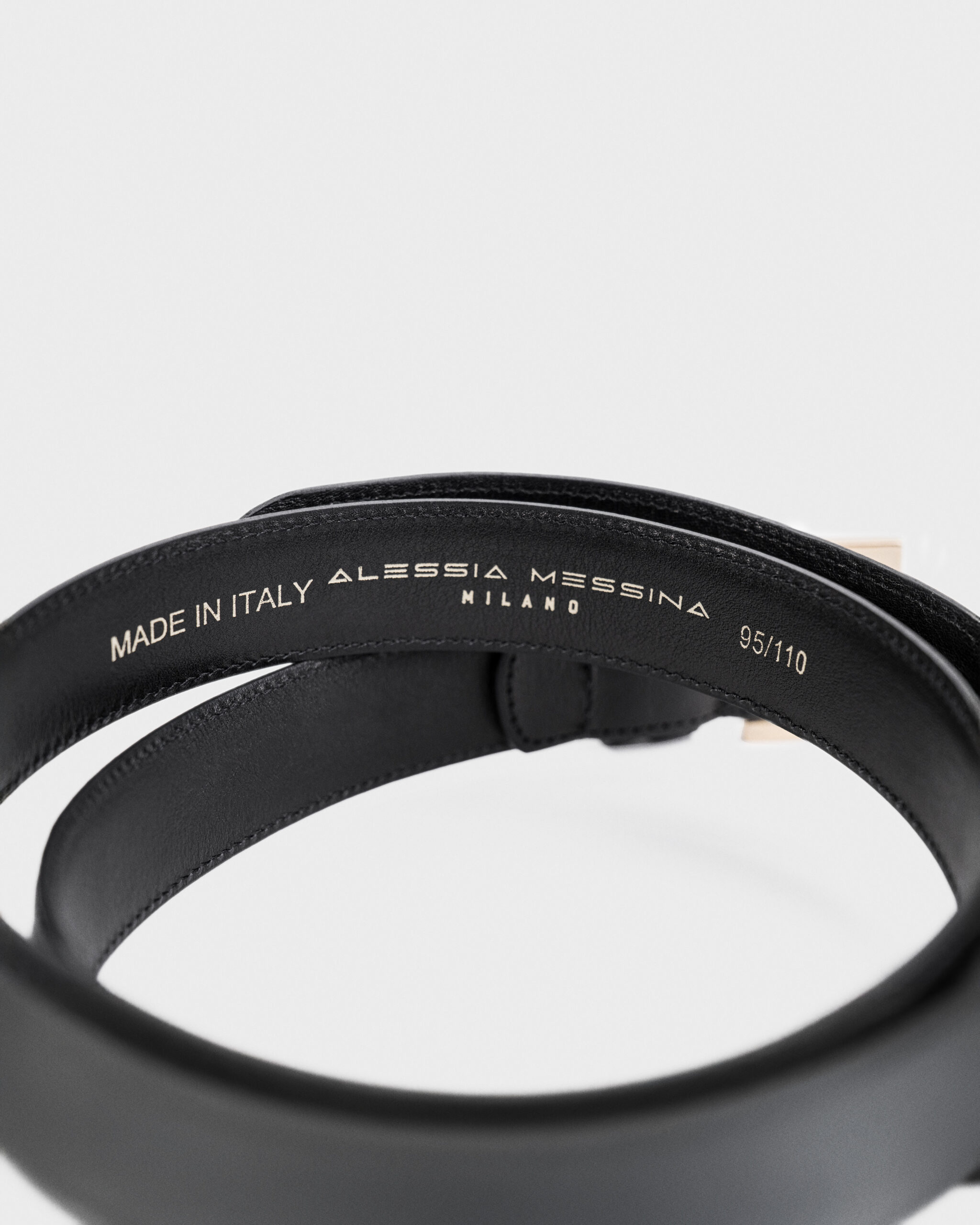Close-up of a black leather bracelet with 'Made in Italy' engraving.