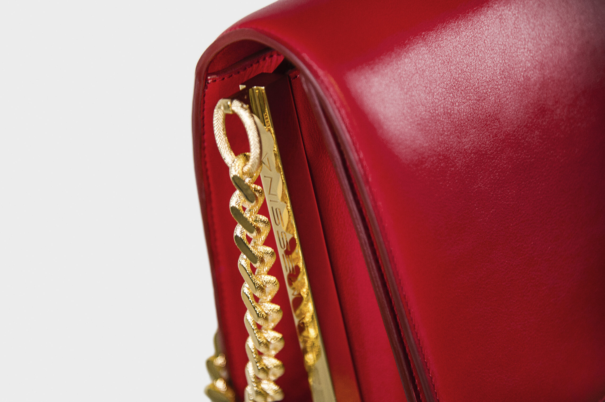 Close-up of a red leather bag with gold chain detail.