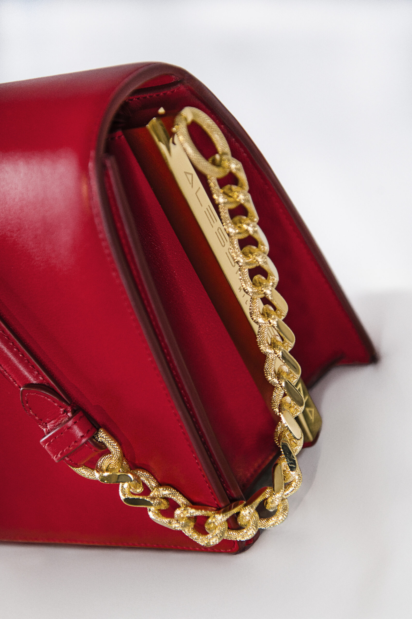 Close-up of a red handbag with a gold chain strap.