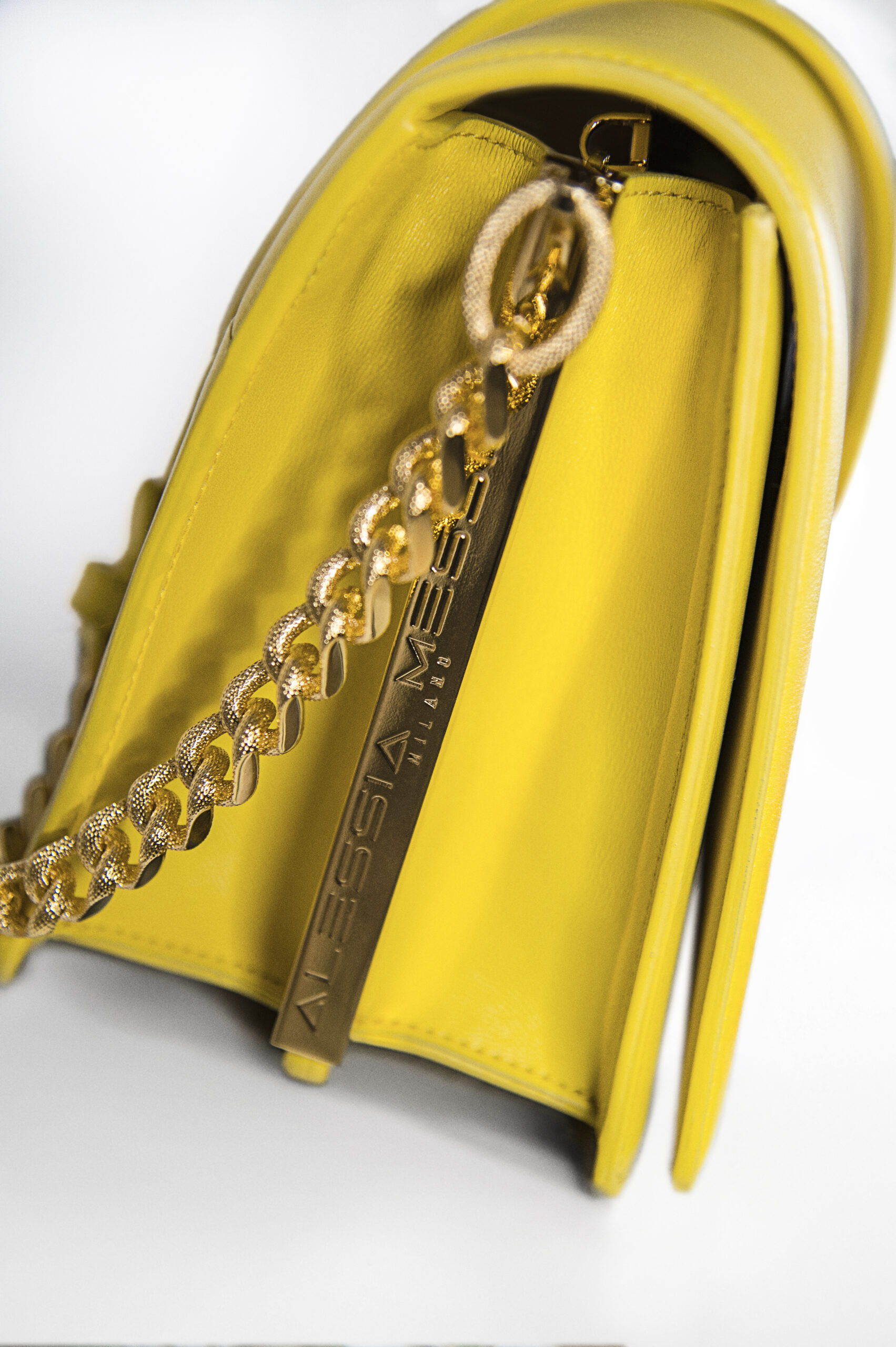 Close-up of a yellow handbag with gold chain and zipper.