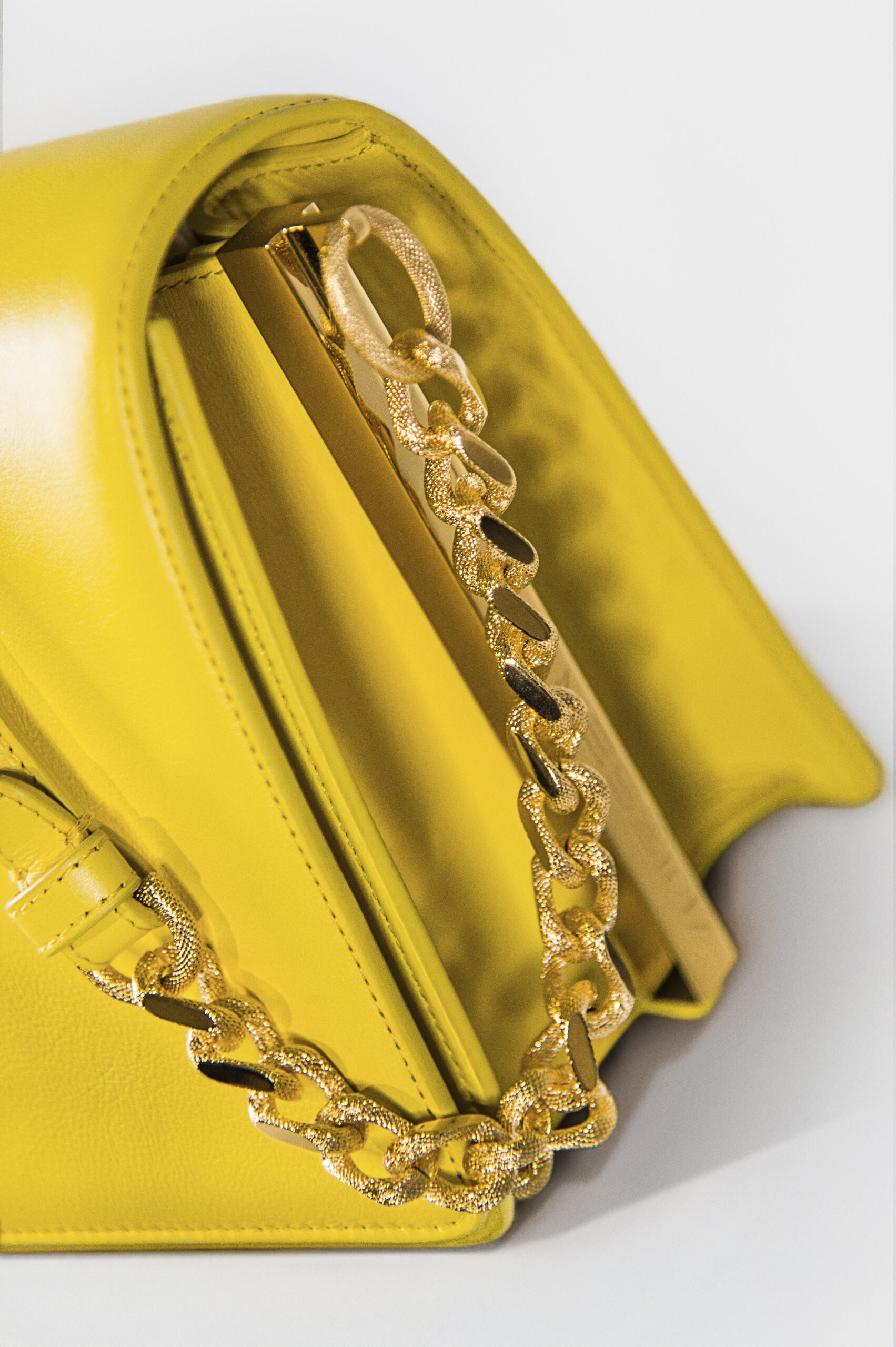 Close-up of a yellow handbag with a gold chain strap.