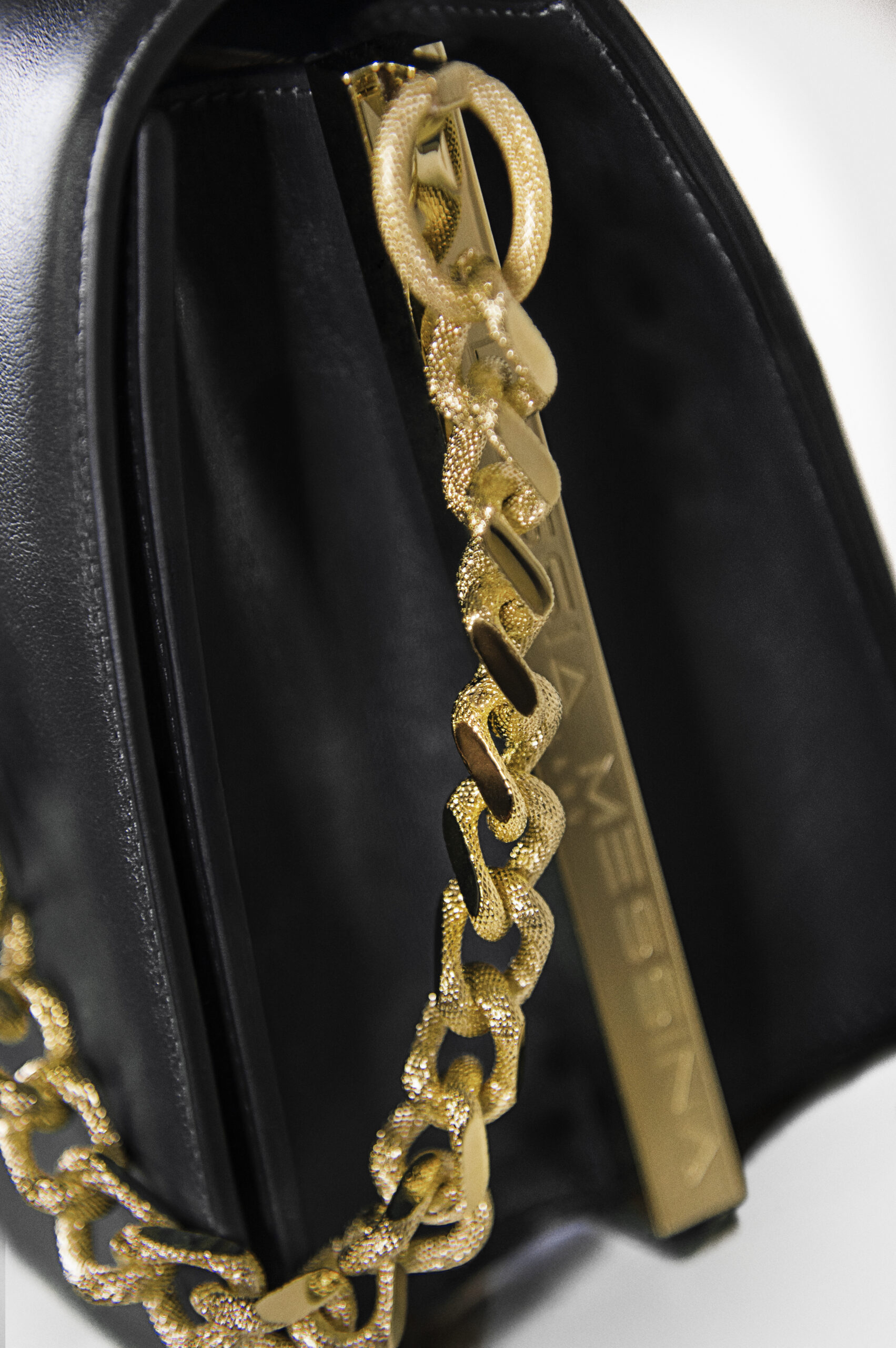 Close-up of a gold chain necklace on black fabric.