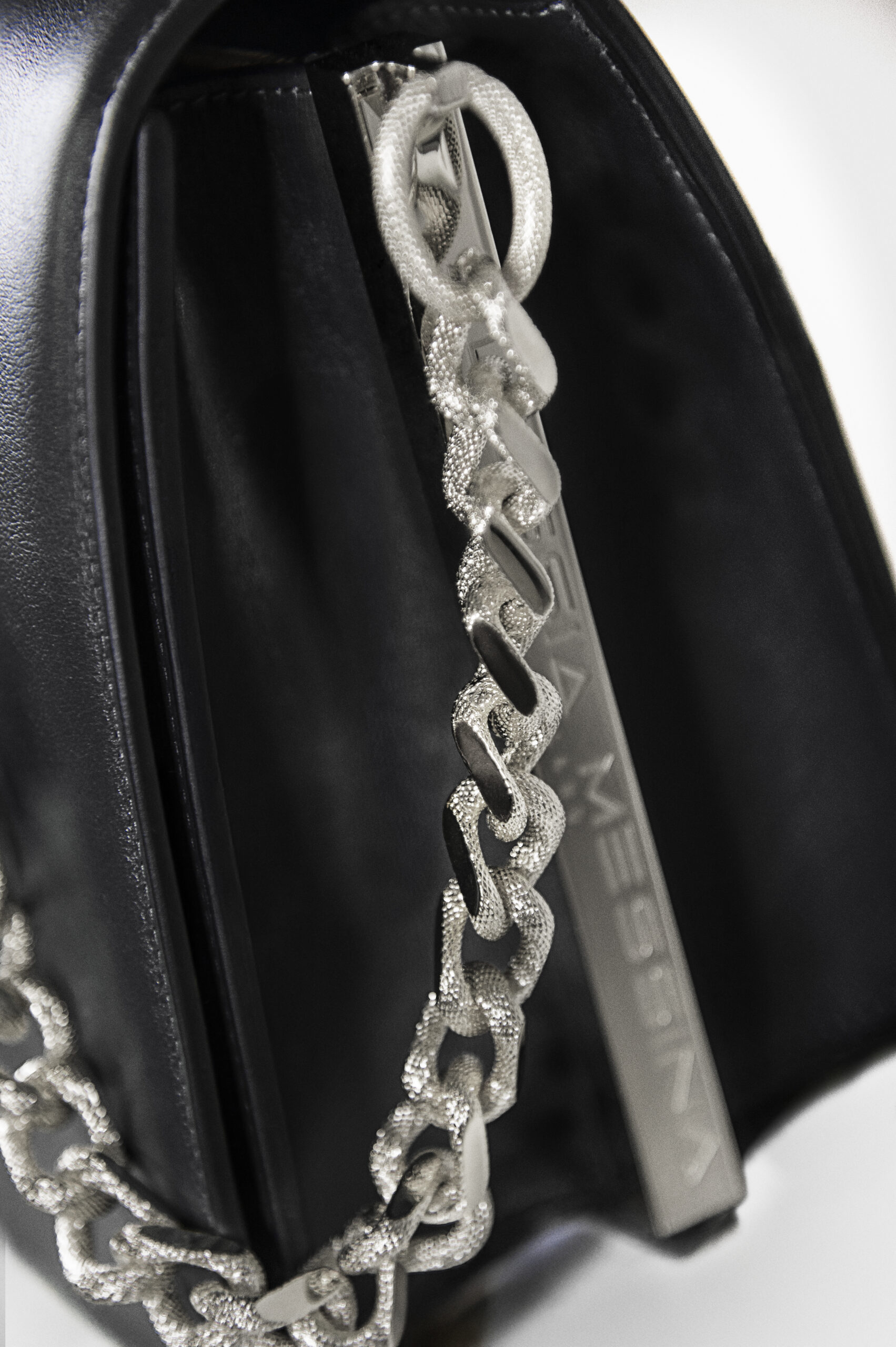 Close-up of a silver chain necklace on black fabric.
