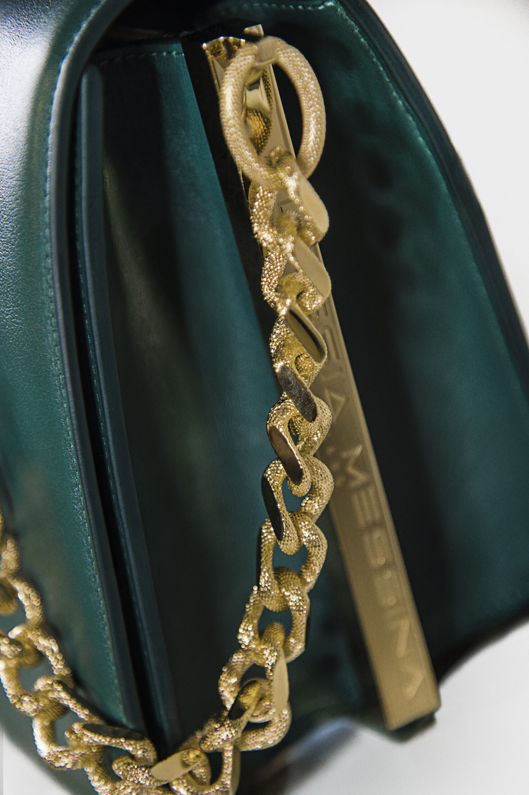 Close-up of a gold chain necklace on green velvet fabric.