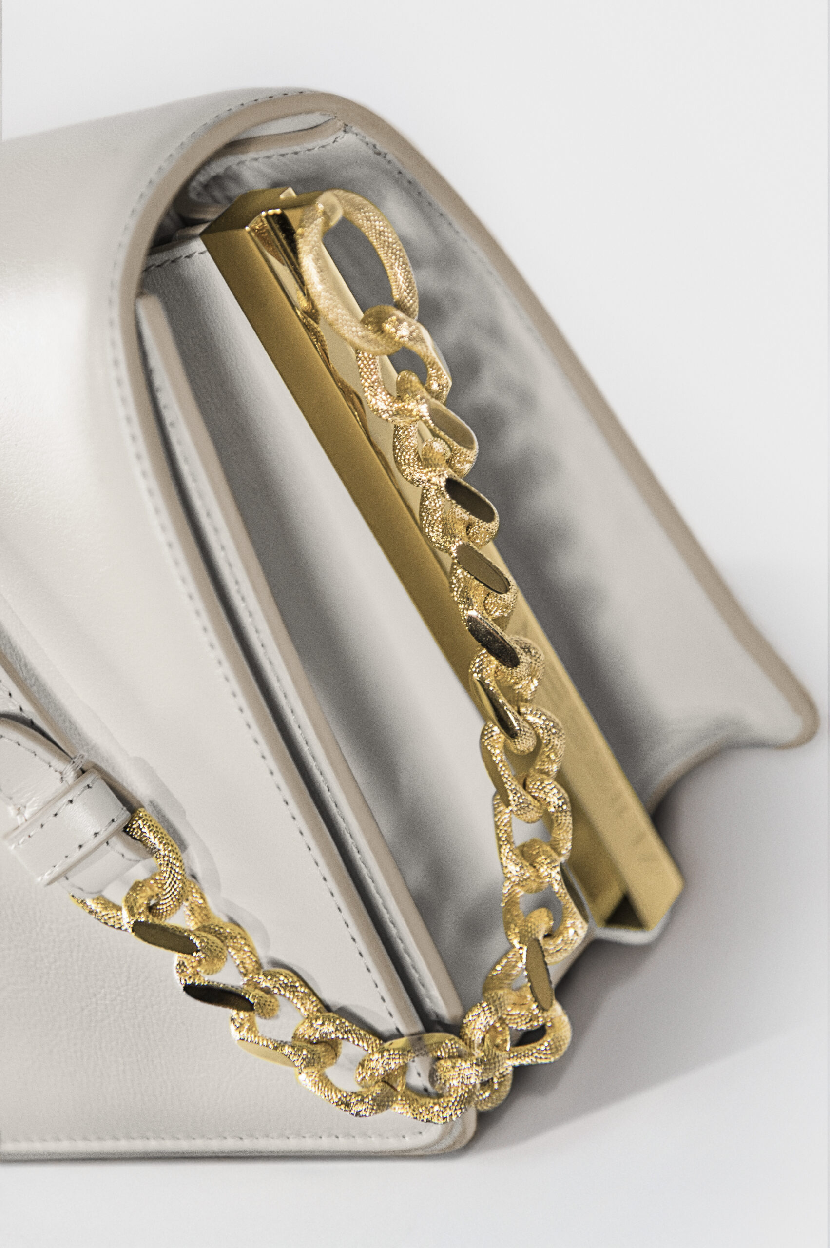 Close-up of a handbag with a gold chain and metallic finish.