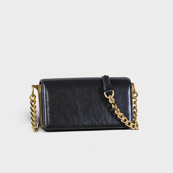 Black leather purse with gold chain strap on gray background.