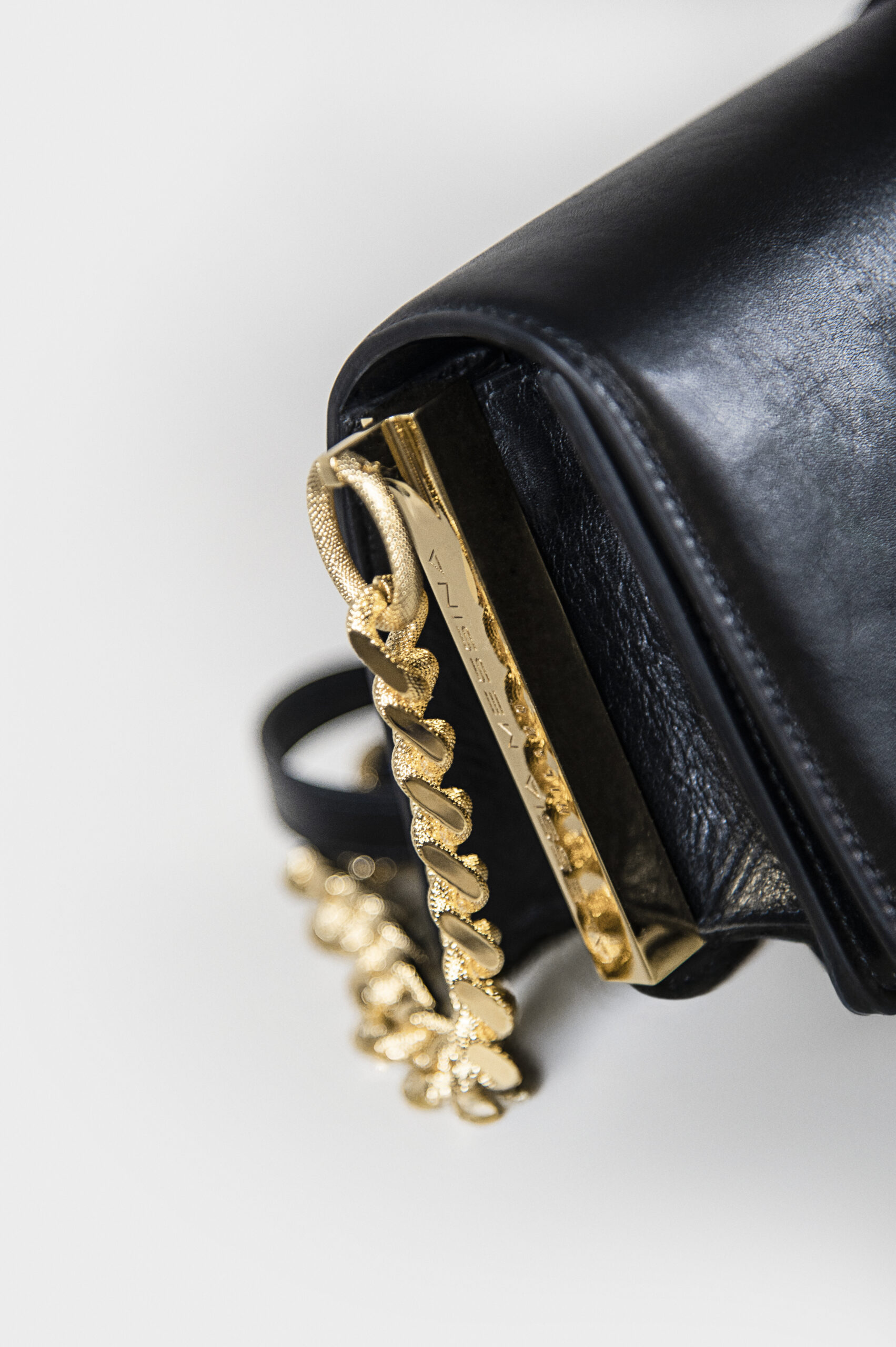 Close-up of a black leather bag with a gold chain detail.