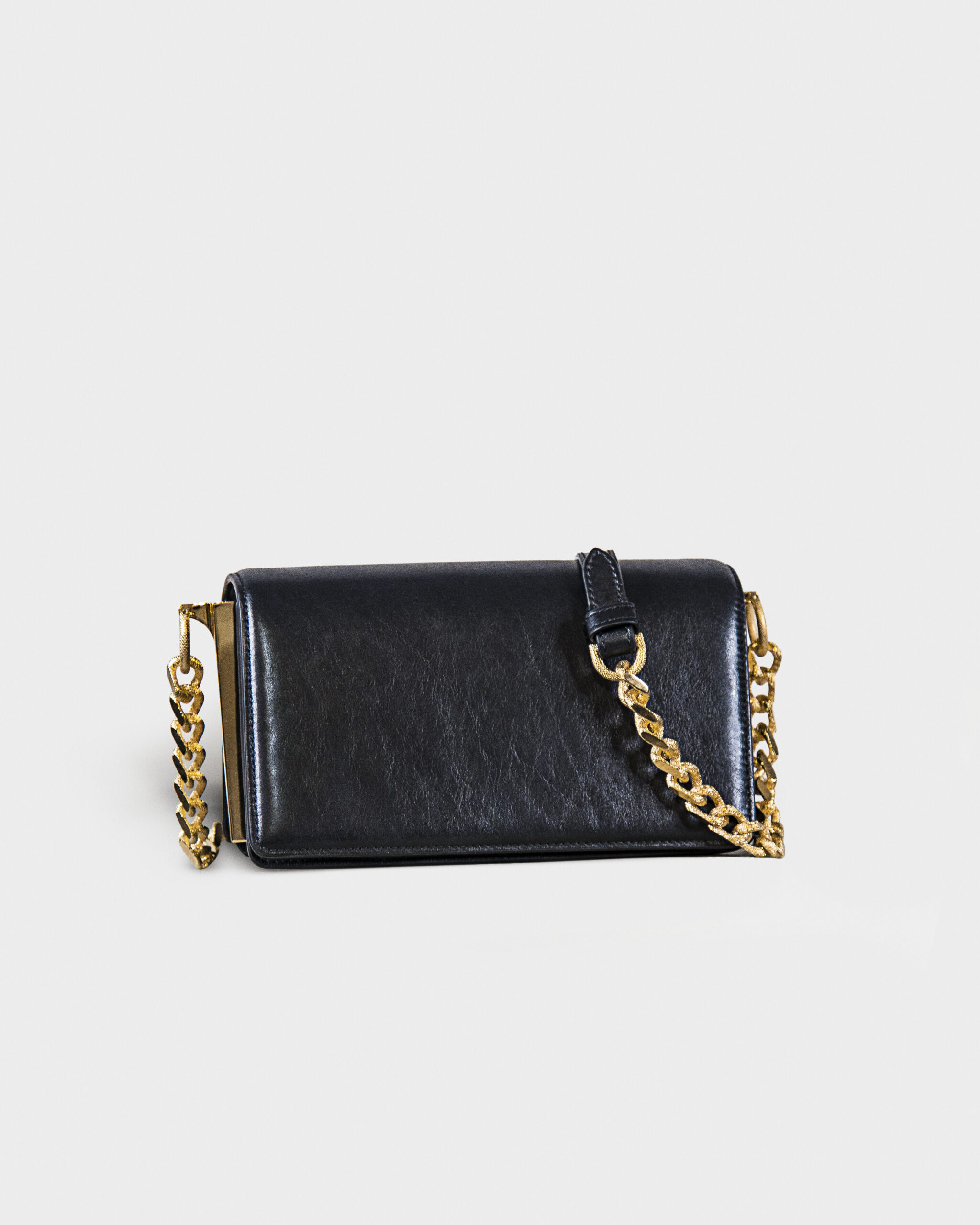 Black leather purse with gold chain strap on gray background.