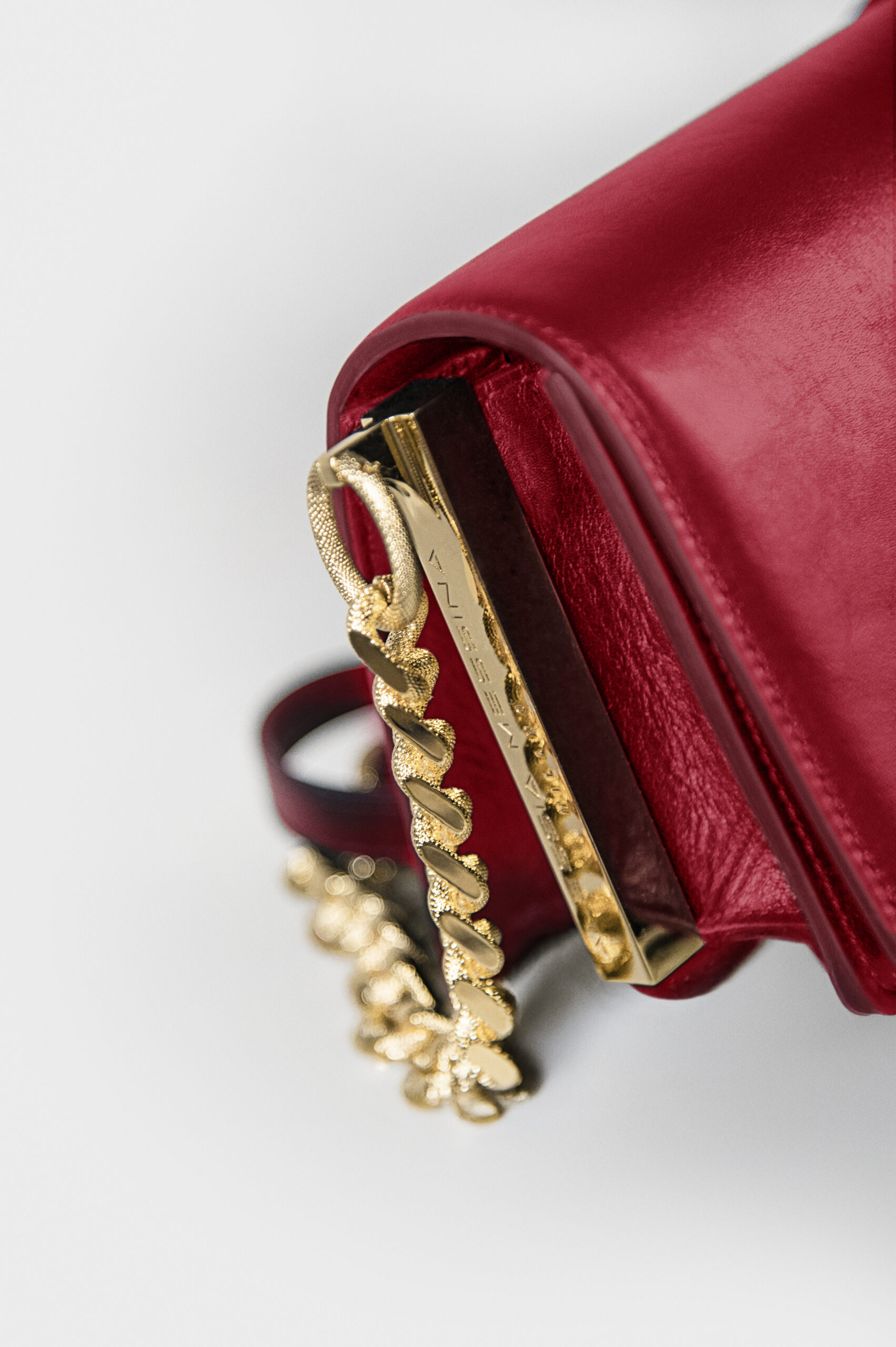 Close-up of a red leather bag with gold chain and zipper details.