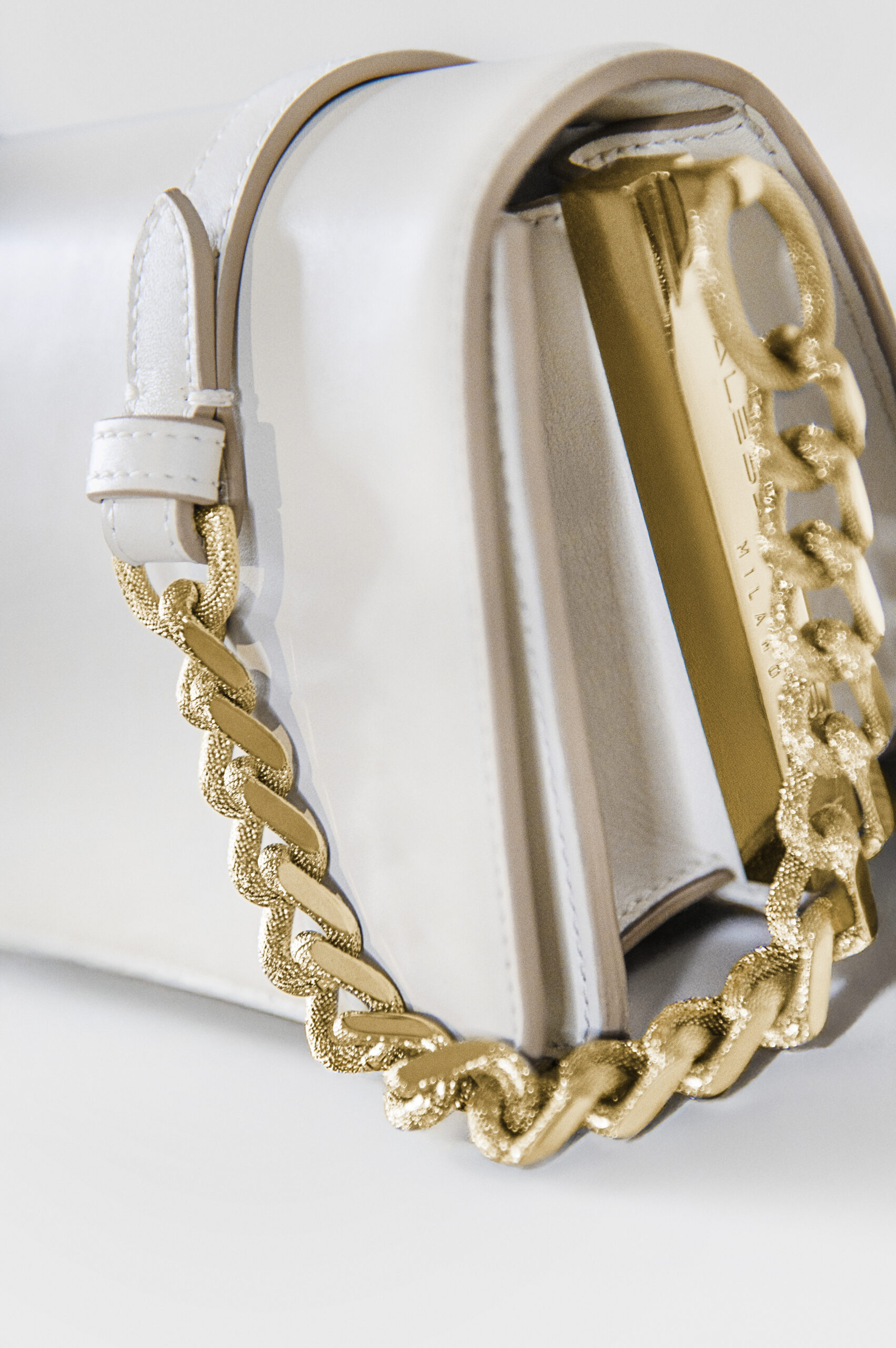 Close-up of a white handbag with a gold chain strap.