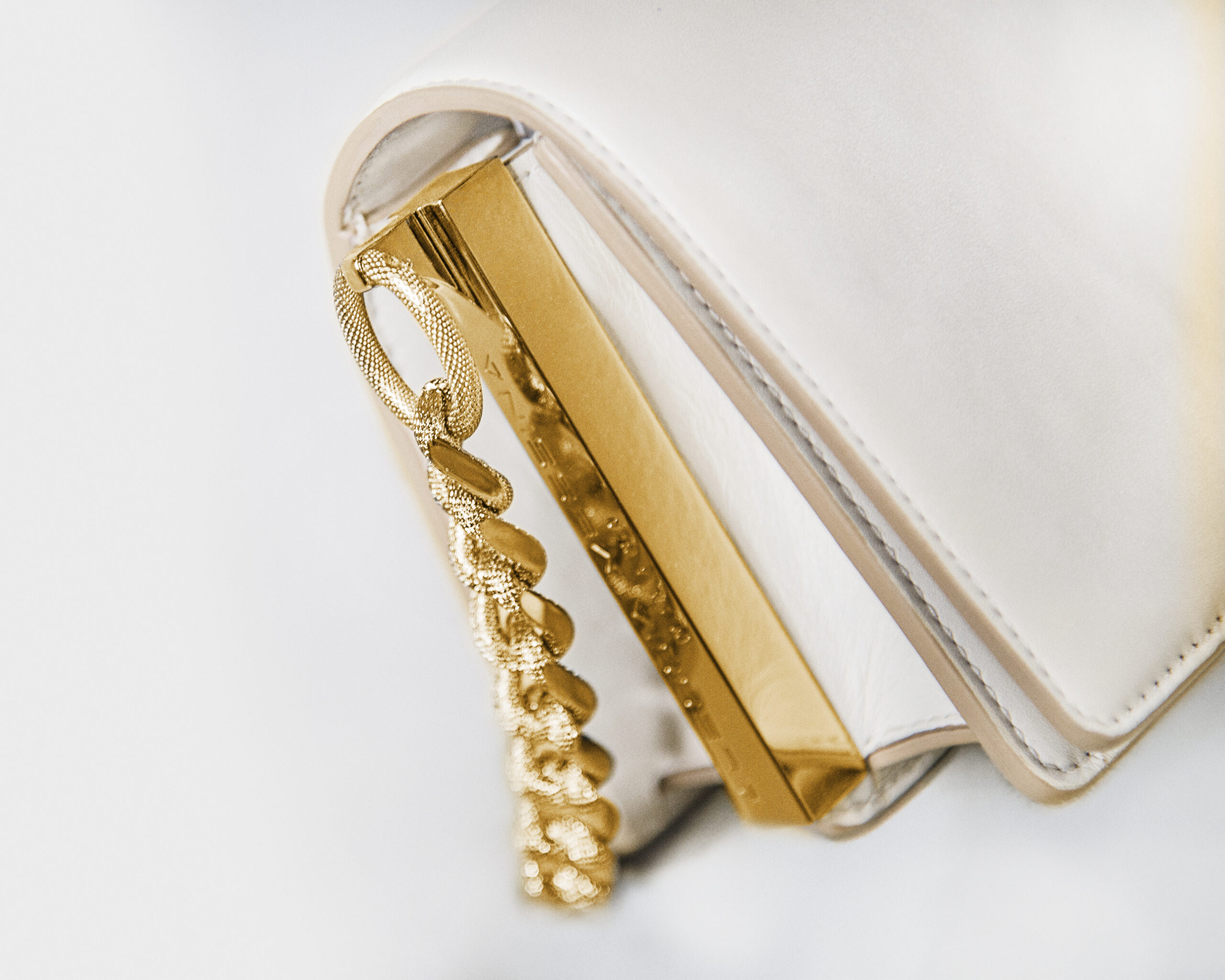 Gold and pearl pendant on a white cord necklace.