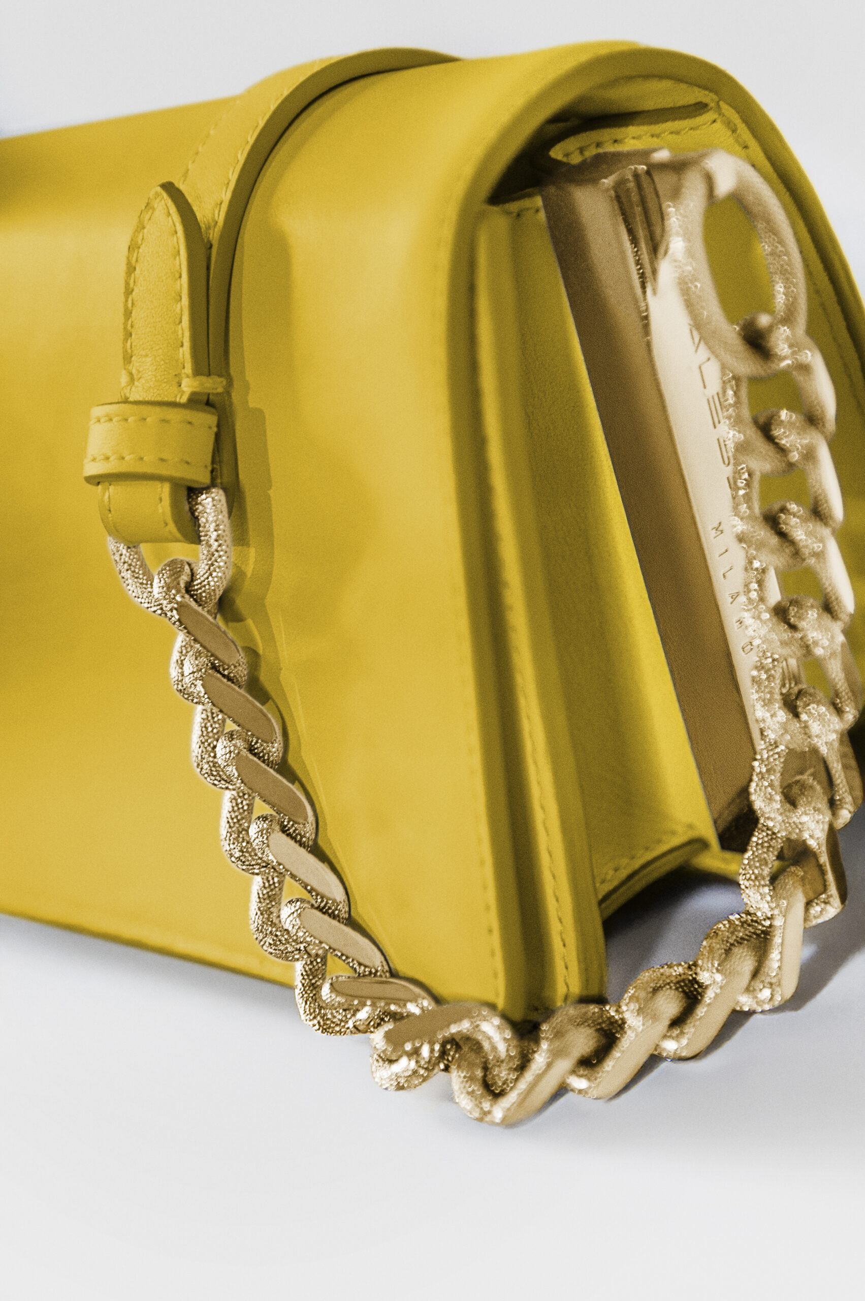 Close-up of a yellow handbag with a gold chain strap.