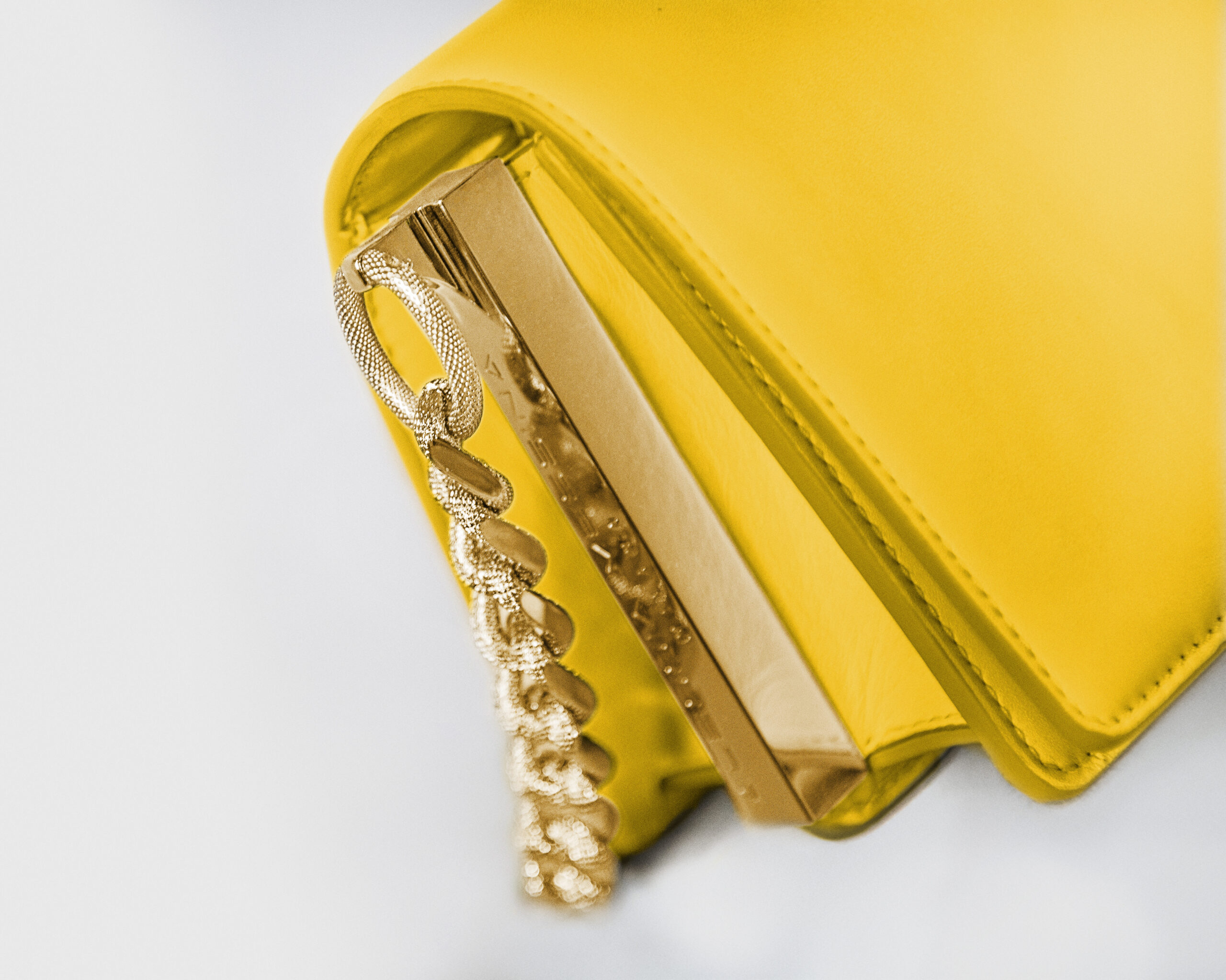 A stylish yellow handbag with a gold chain strap detail.