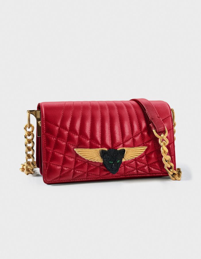 Red quilted leather handbag with gold winged emblem and chain strap.