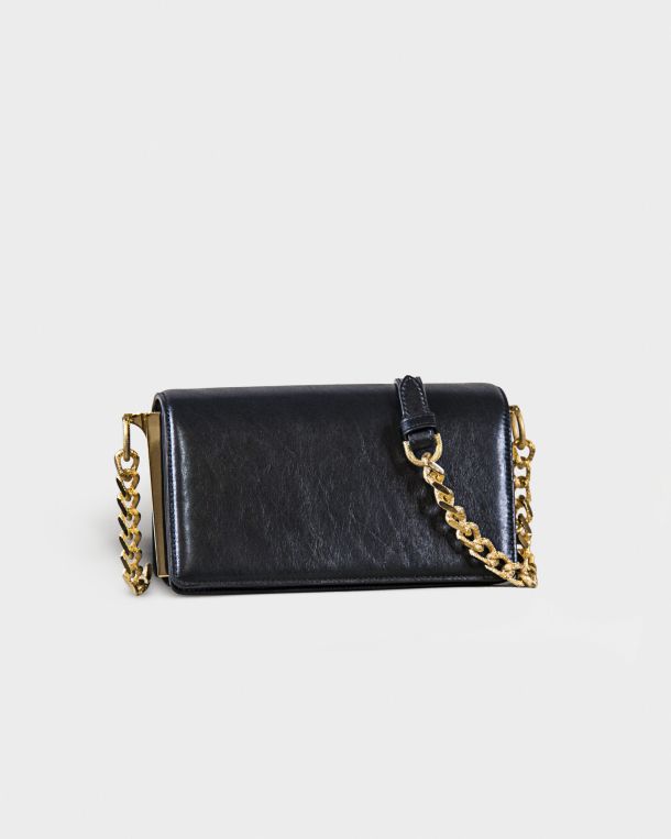 Black leather purse with gold chain strap on gray background.