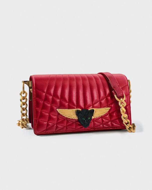 Red quilted leather handbag with gold winged emblem and chain strap.