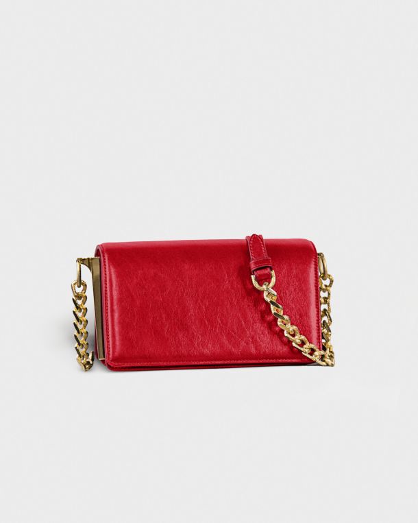 Red leather purse with gold chain strap on white background.