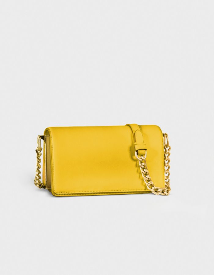 Yellow leather purse with gold chain strap on white background.
